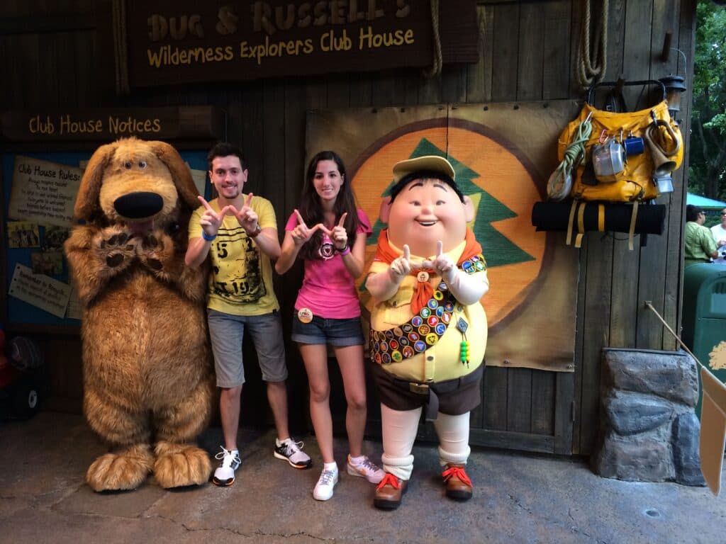 Casal junto aos personagens Russel e seu cachorro Dug do filme Up! Altas Aventuras da Disney Pixar, em um cenário de explorador selvagem, assim como no filme. Todos estão fazendo um W com os dedos, que é o simbolo de Wilderness Explorers "exploradores selvagens" apresentado no filme