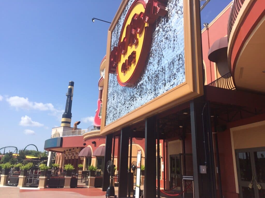 Entrada do restaurante Hard Rock Cafe Orlando, que é o maior do mundo e fica no Universal Citywalk, com suas paredes vermelhas e detalhadas em amarelo e o grande logo da marca ao centro.