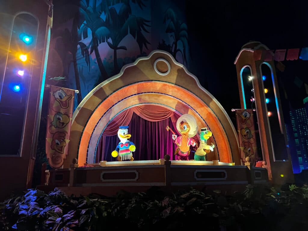 Foto do interior da atração Gran Fiesta Tour Starring The Three Caballeros, onde aparecem os animatrônicos dos personagens Pato Donald, Panchito e José Carioca performando uma apresentação musical.