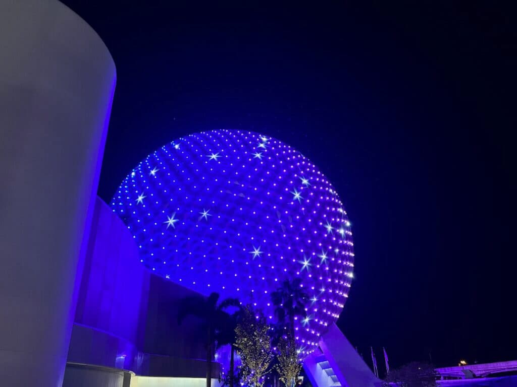 Bola símbolo do Epcot, a Spaceship Earth iluminada a noite com uma coloração azul e roxo no parque de diversões Epcot em Walt Disney World Resort Florida