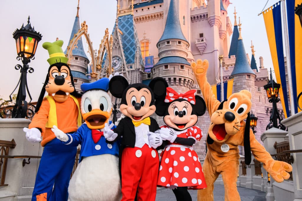 Os personagens Mickey Mouse, Minnie Mouse, Pluto, Pato Donald e Pateta posando para foto em frente ao Castelo da Cinderela no parque de diversões Magic Kingdom em Walt Disney World Resort Florida