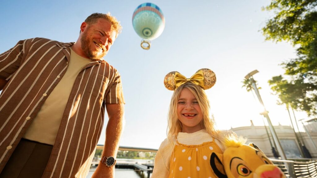 Pai e filha passam um dia agradável em Disney Springs, o balão ao fundo mostra uma das experiências mais icônicas no local