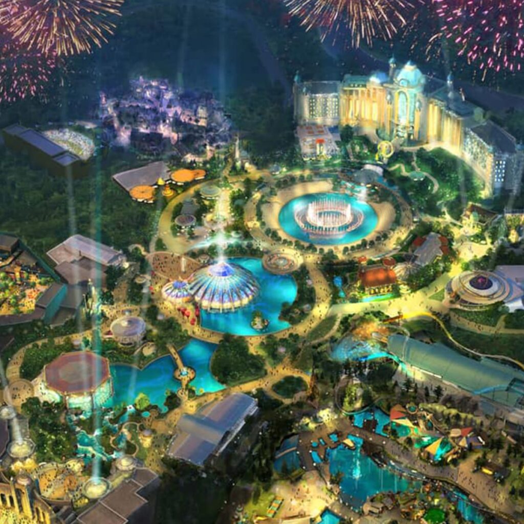Imagem de conceito artístico de como será o novo parque Universal's Epic Universe. Na imagem dá pra notar um hotel bem grande ao fundo, que parece abraçar a área. Ao centro podemos ver lagos circulares com fontes, estruturas e pontes. Há também muitos feixes de luz que iluminam todo o ambiente, que parece ser um hub central para todas as áreas do parque