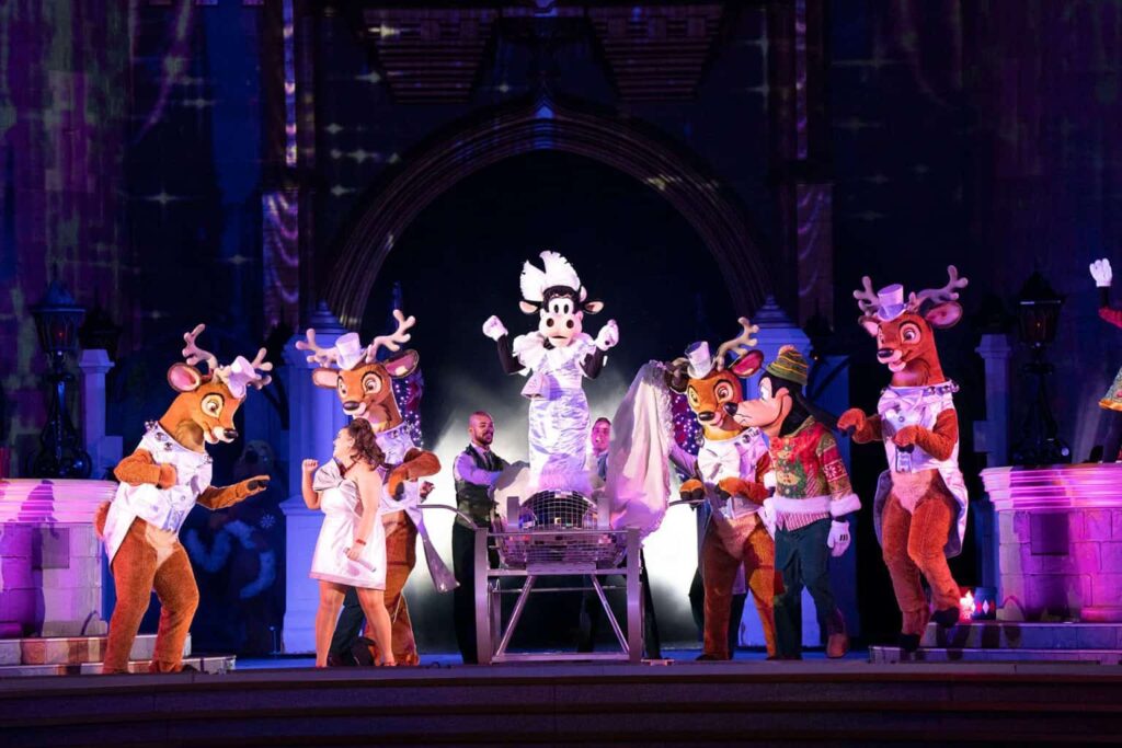 Foto da Clarabela, junto a Renas e o Pateta no palco em frente o castelo da Cinderela no Magic Kingdom, durante as celebrações de natal