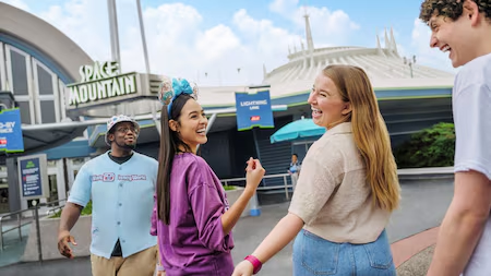 Grupo de quatro amigos, em frente a montanha russa Space Mountain n Magic Kingdom na Disney World em Orlando, se dirigem super empolgados até a entrada da atração, onde usarão seu Lightning Lane para furar a fila