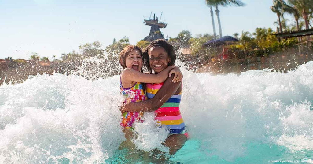 duas meninas se abraçam enquanto se divertem ao serem atingidas por uma onda na maior piscina de ondas de parque aquático, localizado na Disney, o Typhoon Lagoon
