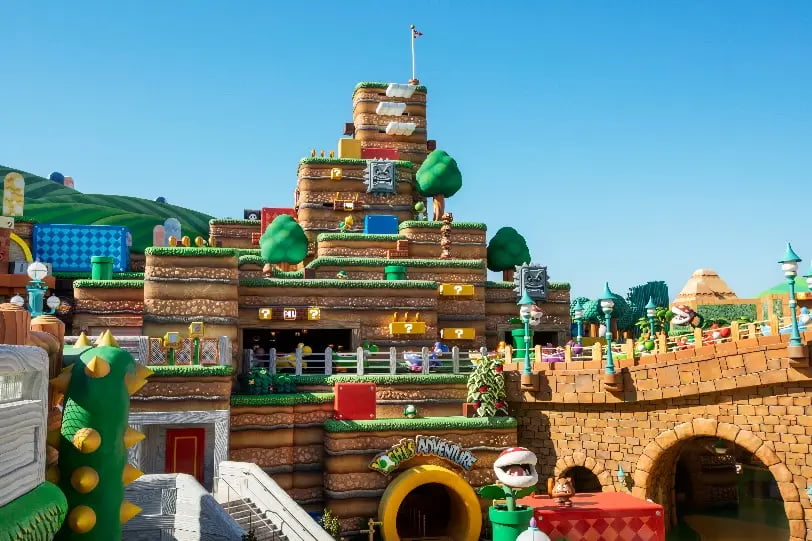 Foto da área de Super Nintendo World, mostra cenário de Super Mario Bros com plantas carnívoras, moedinhas, Yoshis, canos, castelo e muito mais, no novo parque da Universal Orlando Epic Universe