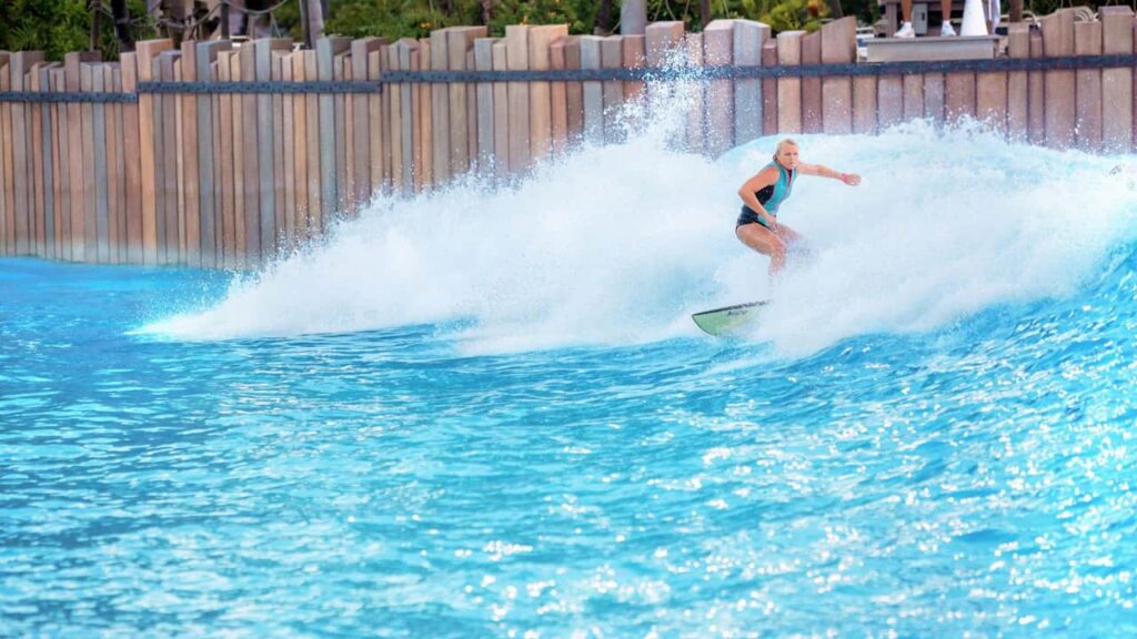 Mulher surfa na piscina de onda com as maiores ondas de parques aquáticos, no Disney's Typhoon Lagoon