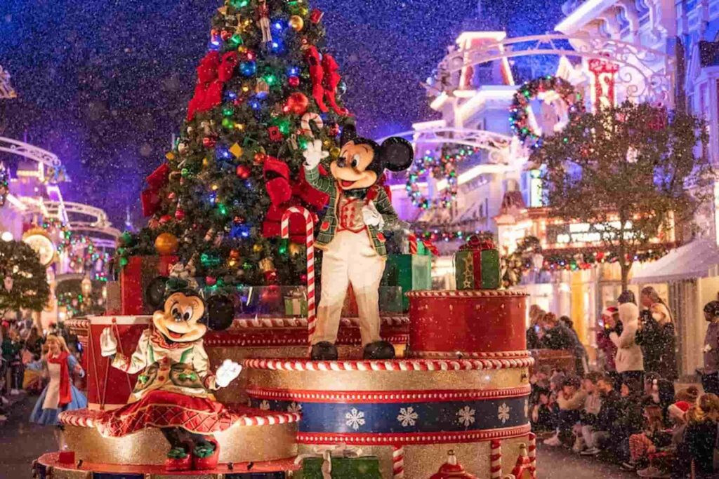 Mickey e Minnie Mouse no carro alegórico com árvore de natal, passando pela Main Street USA no parque Magic Kingdom, em Walt Disney World, Orlando, com neve artificial ao fundo e luzinhas natalinas