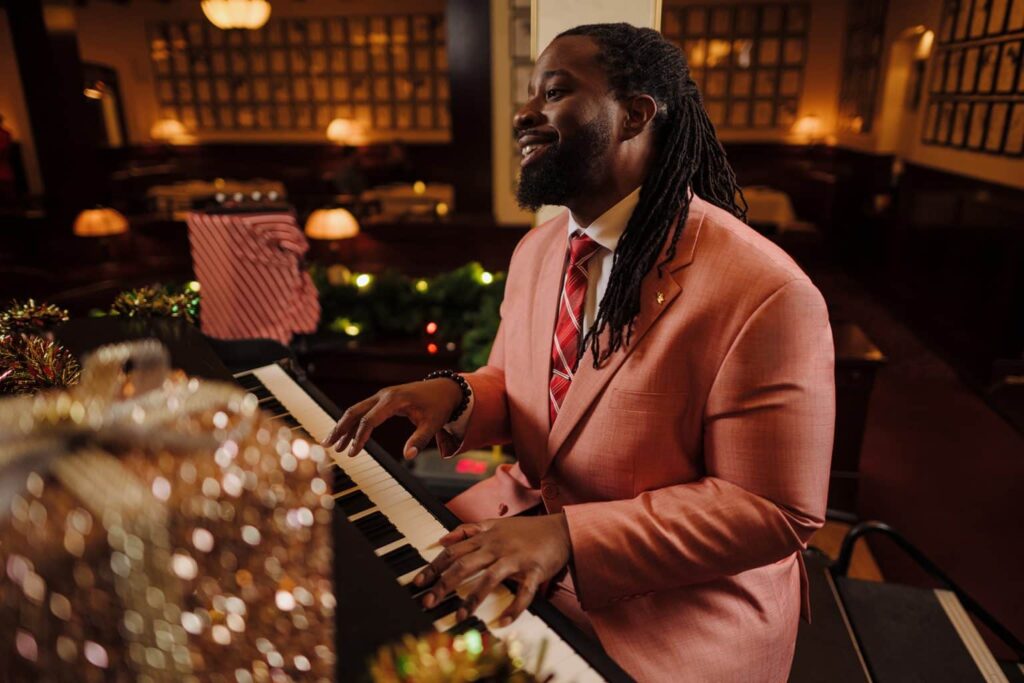 Homem sorridente toca piano durante a festa de natal Jollywood Nights no Hollywood Studios