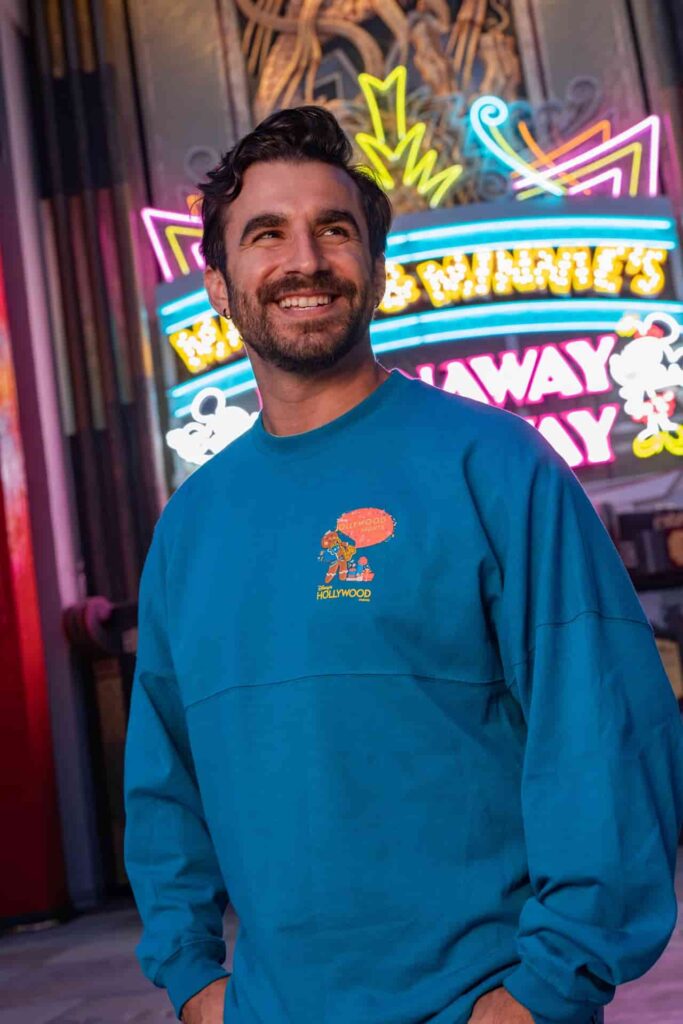 Homem em frente ao teatro chinês, na atração Mickey e Minnie Runaway Railway, exibe a Spirit Jersey da festa Jollywood Nights, a festa de Natal do parque temático Hollywood Studios na Disney