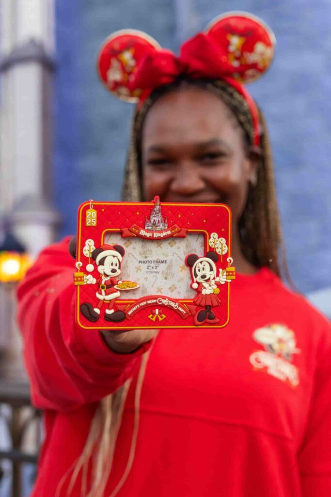 Mulher mostra sorrindo moldura de fotos temática da festa de Natal do Magic Kingdom na Disney, a Mickey's Very Merry Christmas Party, em Orlando