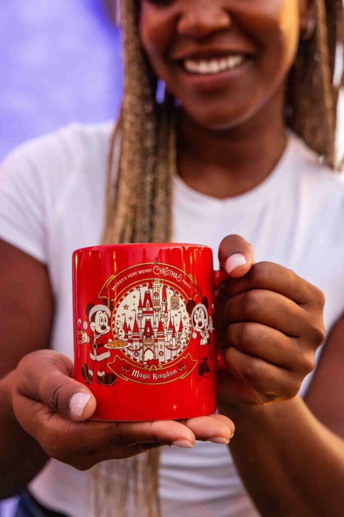Mulher mostra caneca temática da festa de Natal do Magic Kingdom na Disney, a Mickey's Very Merry Christmas Party