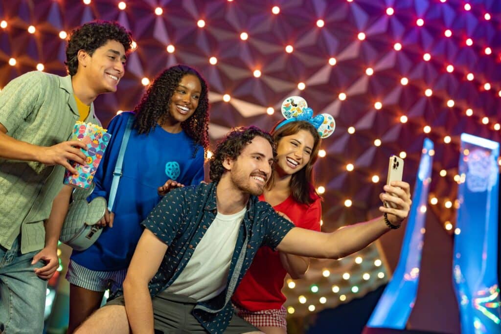 Um jovem homem tira uma selfie dele com os amigos se divertidno no Epcot no evento After Hours que acontece a noite na Disney