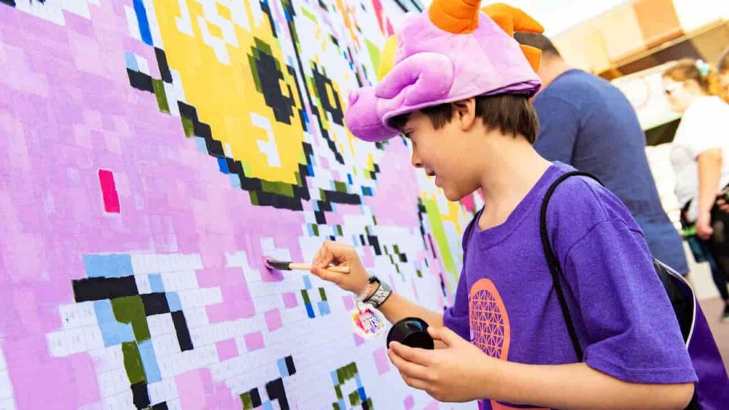 Menino com chapéu do Figment, mascote do parque de diversões Epcot da Disney, pinta um mural de artes do mesmo personagem, durante o Festival of The Arts na Disney de Orlando