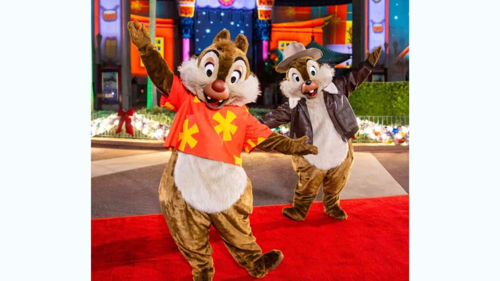 Tico e Teco com suas roupas de Ducktales, posam de braços abertos em frente ao teatro chinês no parque de diversões Disney's Hollywood Studios durante a festa de natal Jollywood Nights