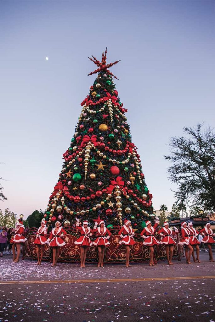 Árvore de Natal com dançarinas vestidas em trajes especiais natalinos que fazem alusão a roupa do Papai Noel, no parque de diversões Universal Studios Orlando