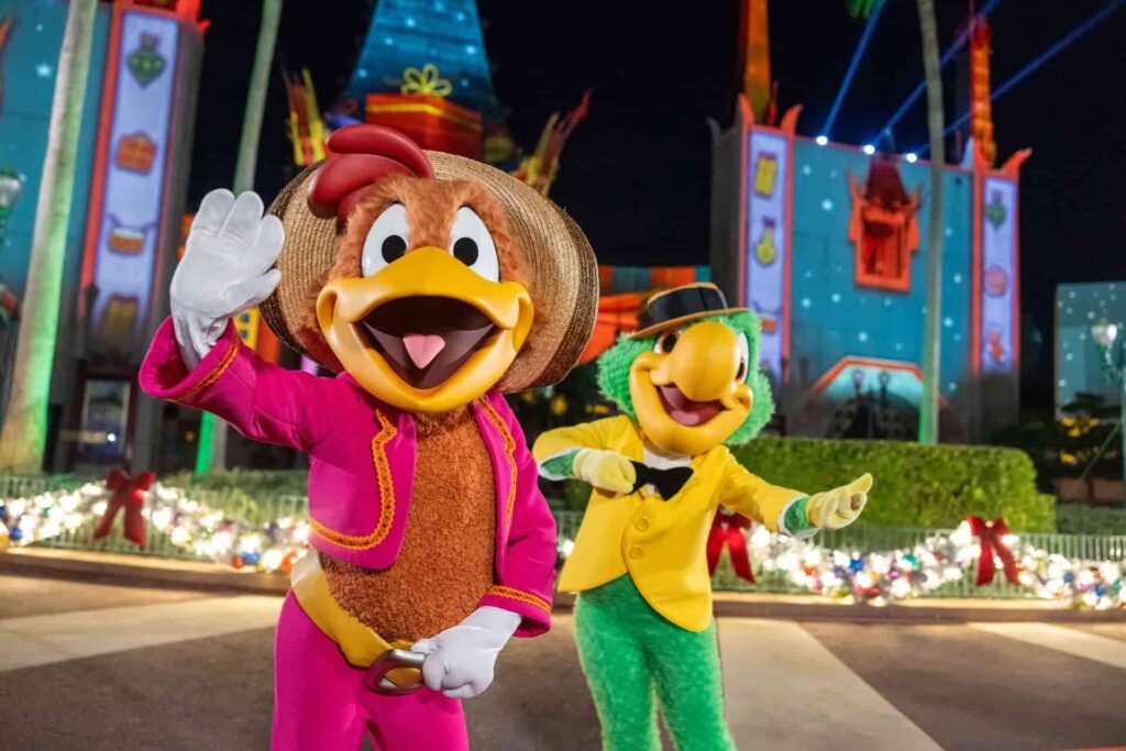 Panchito e Zé Carioca posam cumprimentando os visitantes em frente ao teatro chinês no parque de diversões Disney's Hollywood Studios durante a festa de natal Jollywood Nights