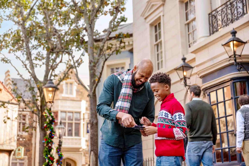 Pai e filho se divertem brincando de caça ao tesouro do Olaf no parque Epcot, na Disney, durante as festas de final de ano, no Festival of Holidays