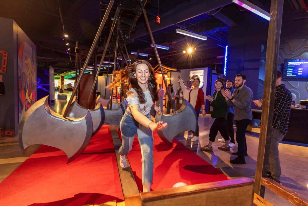 Mulher corre para conseguir ganhar a competição enquanto seus amigos assistem e torcem por ela no Level 99, que vai inaugurar em Disney Springs em 2026