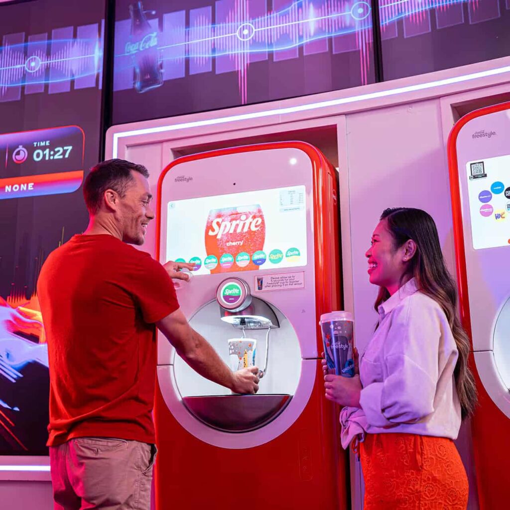 Casal conversa enquanto enchem seus copos coca cola freestyle com refil gratuito