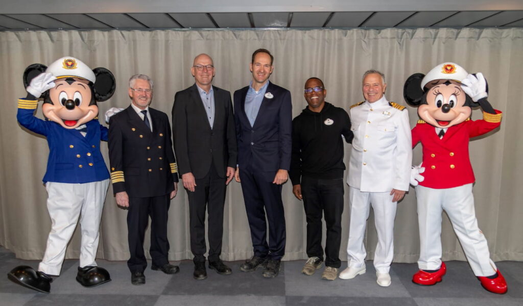 Mickey Mouse, Capitão Wolfgang, Bernd Eikens, Philip Gennote, Mike Davie, Capitão Fabian, e Minnie Mouse, posam felizes para foto celebrando o navio da Disney Cruise Line, o Disney Adventure