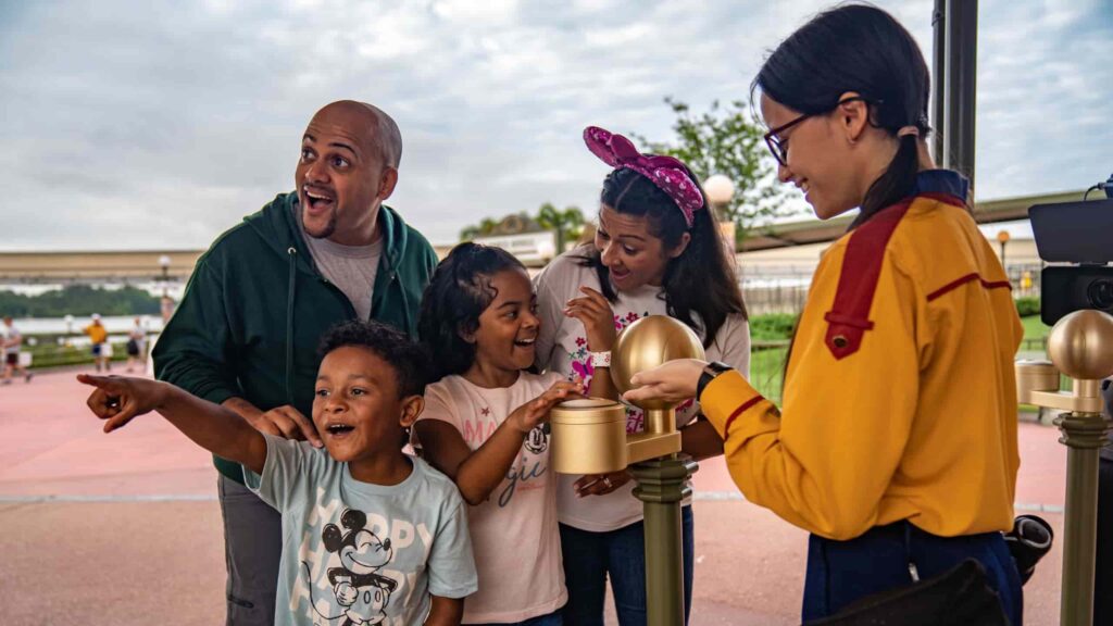 casal entra no parque de diversões da Disney junto aos seus filhos que mostram encantamento e animação