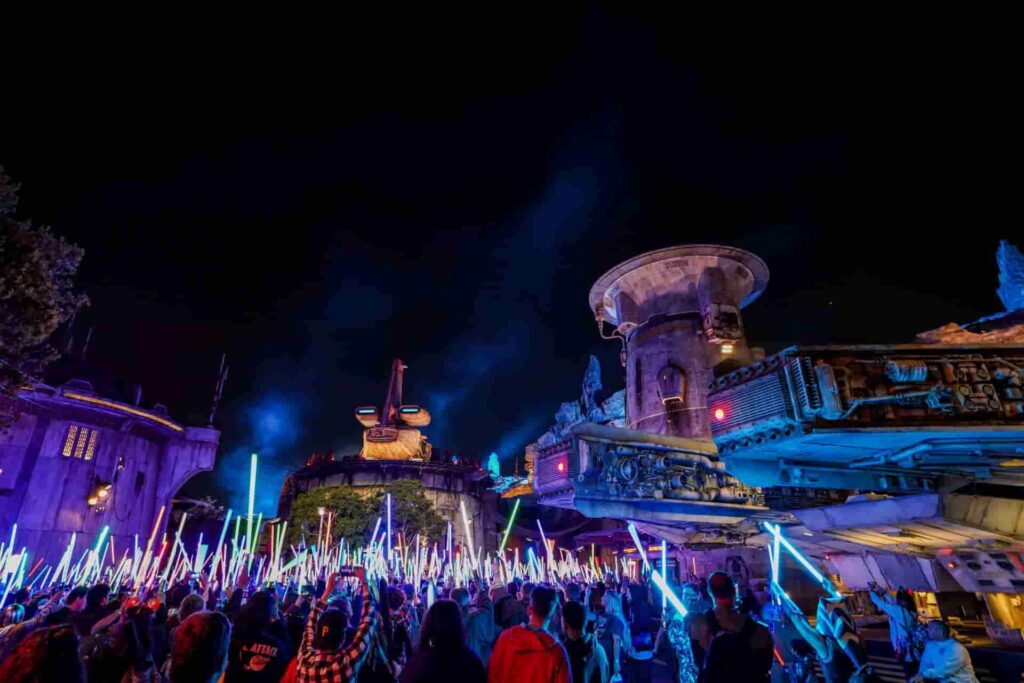 Fãs de Star Wars levantam seus sabres de luz em Batuu na Disneyland Califórnia durante o evento After Dark Star Wars Nite