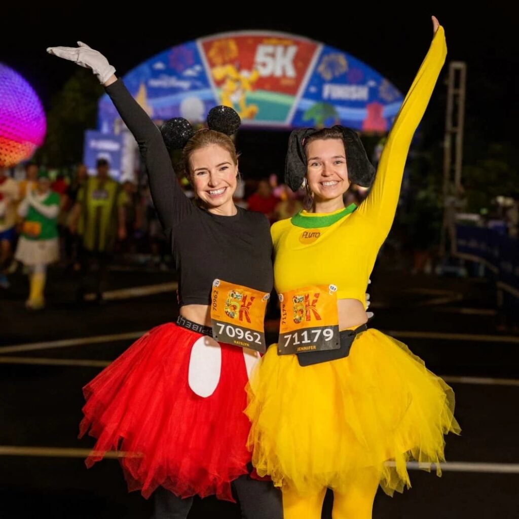 Mulheres fantasiadas de Mickey e Pluto felizes ao completar a corrida da RunDisney de 5k em Walt Disney World Resort