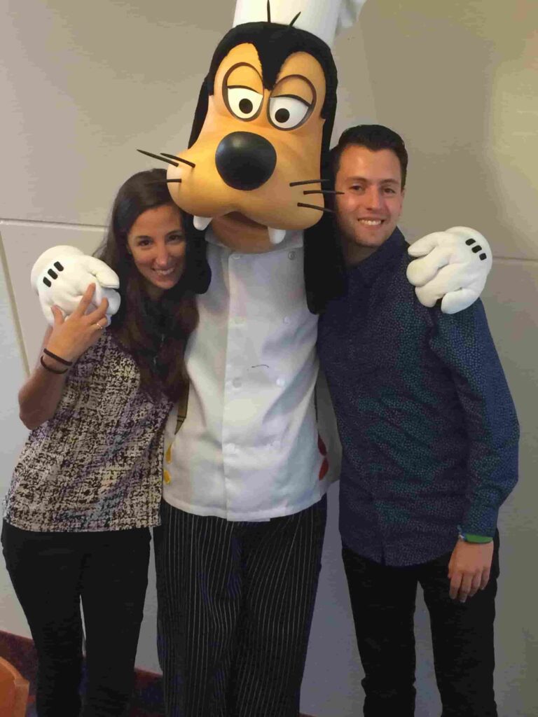 Casal posa para foto com o Pateta no restaurante Chef Mickey's que tem café da manhã e jantar com personagens