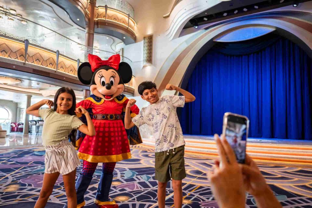 Crianças posam mostrando seus músculos junto a Minnie Mouse heroína no navio da Disney