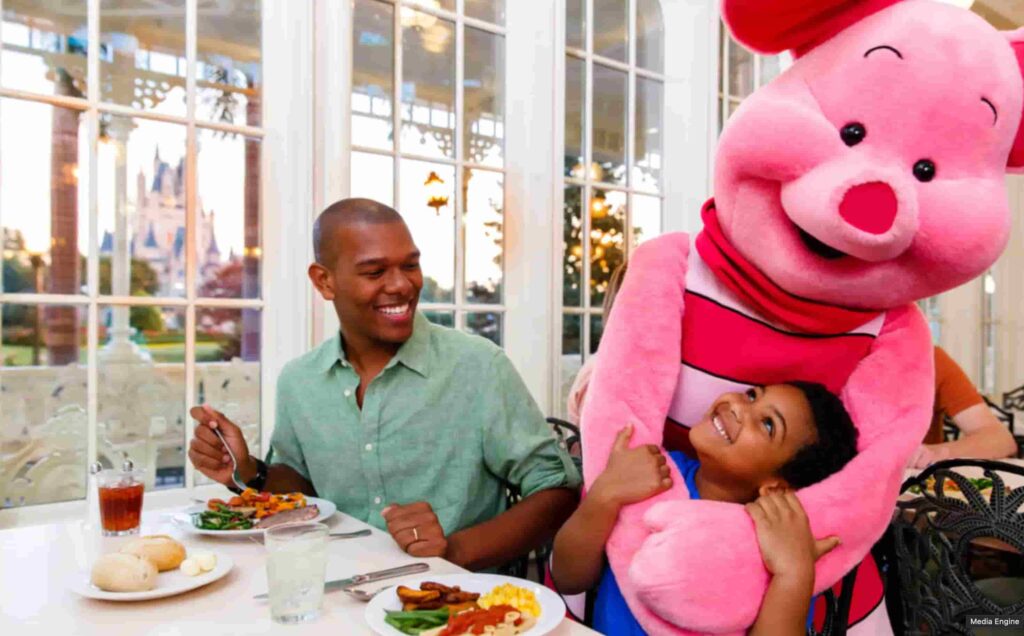 Leitão brinca com criança enquanto o pai observa feliz no restaurante Crystal Palace onde é possível encontrar o Ursinho Pooh e seus amigos durante refeições no café da manhã, almoço e jantar