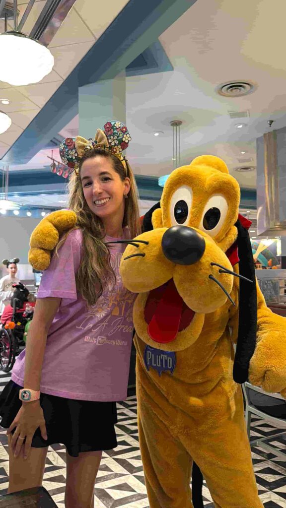 Mulher posa com o Pluto durante refeição no restaurante Hollywood & Vine no Hollywood Studios que oferece experiência com personagens no Café da manhã, almoço e jantar