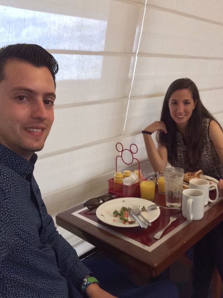 Casal sentado na mesa comendo café da manhã no restaurante Chef Mickey's que tem café da manhã e jantar com personagens
