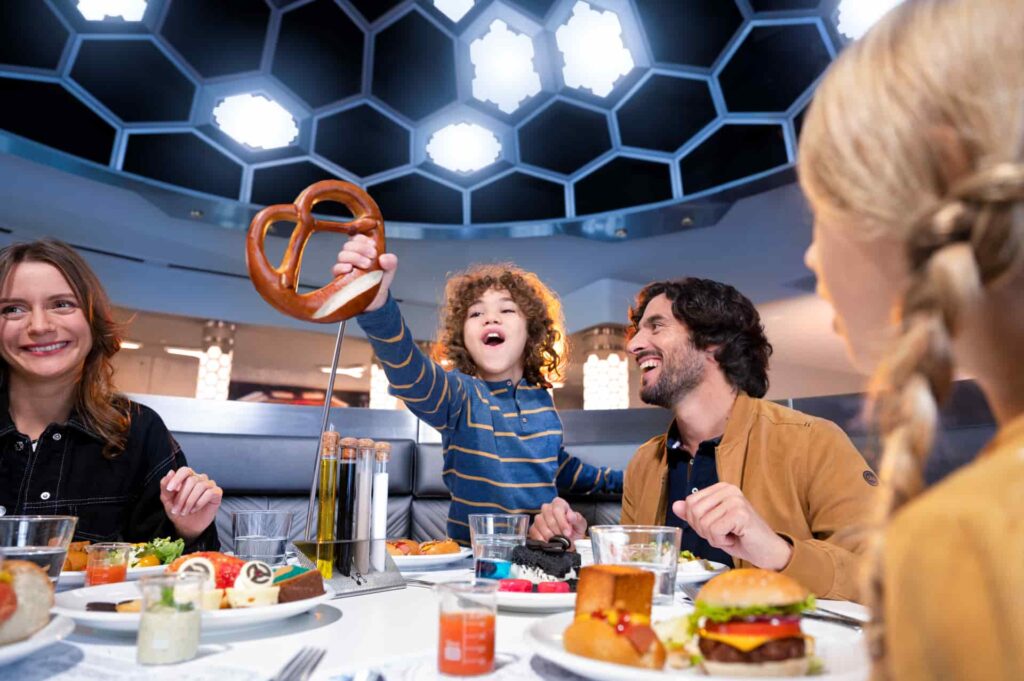 Família come um pretzel gigante na Pym Kitchen, restaurante da Marvel que faz alusão ao homem formiga e serve comidas de diversos tamanhos na Disneyland Paris