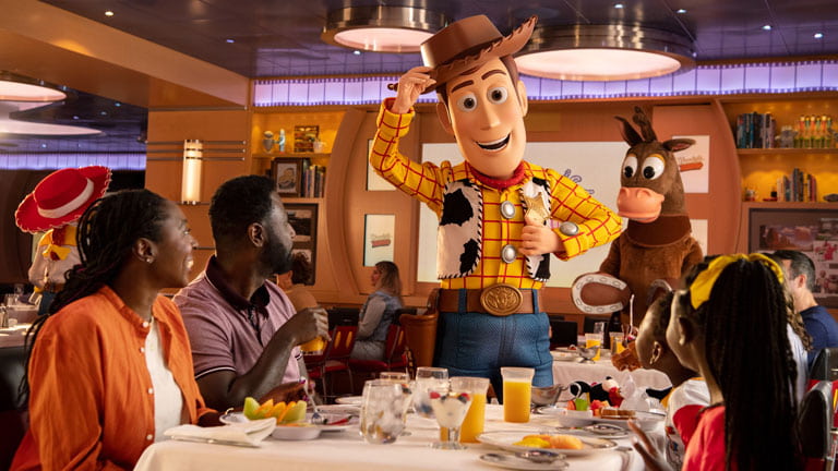 Woody de Toy Story cumprimenta família enquanto comem no restaurante temático Animator's Palate no Disney Cruise Line e Bala no Alvo também aparece mais ao fundo