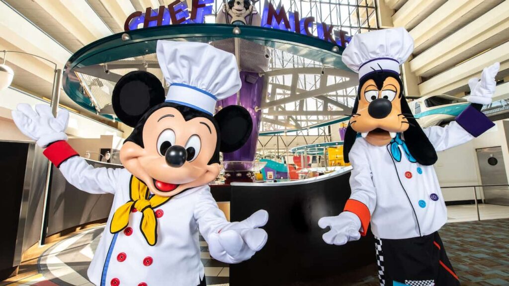 Mickey e Pateta vestidos de chef de cozinha no restaurante Chef Mickey's que tem café da manhã e jantar com personagens