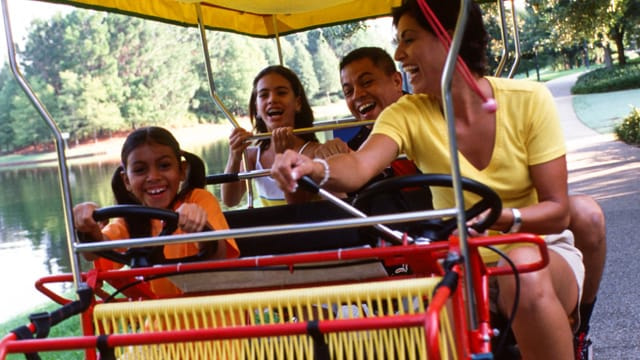 Familia passeando de surrey bike pelo Disney Old Key West Resort, mais um hotel de luxo dentro do complexo Walt Disney World em Orlando na Florida