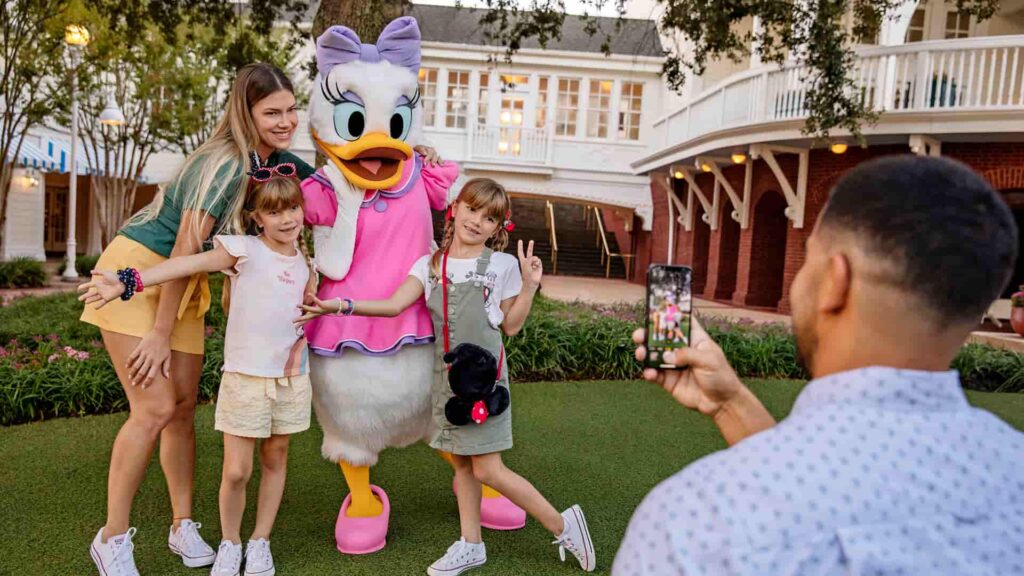 Pai fotografa filhas e esposa junto a Margarida no jardim do hotel Disney's Boardwalk, um hotel de luxo em Walt Disney World resort