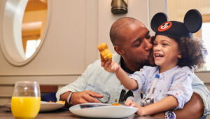 Pai e filho trocam momento de carinho e diversão enquanto comem waffle do Mickey no restaurante Ale & Compass no hotel Disney's Yatch Club na Disney World
