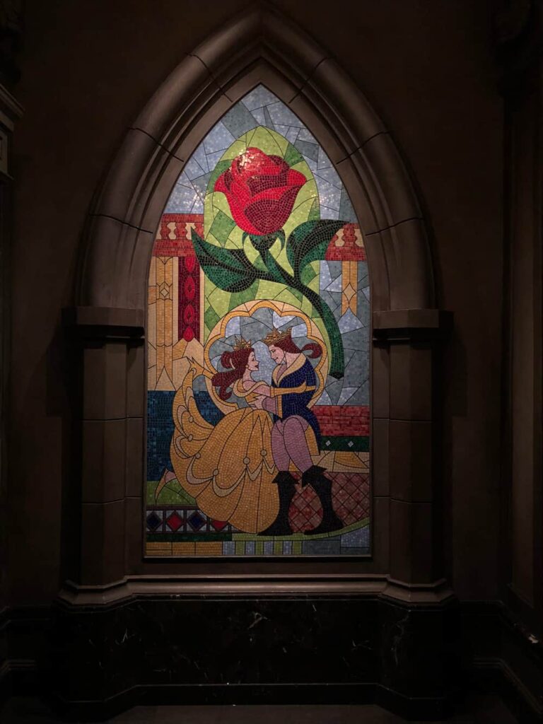 Vitral com a Bela e o Principe Adam dançando no baile com a Rosa tema do filme ao fundo dentro do restaurante Be Our Guest em Walt Disney World Resort no Magic Kingdom