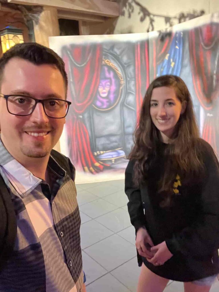 Casal posa em frente ao cenário no Storybook Dining at Artist Point, restaurante com personagens no Wilderness Lodge que conta com Zangado, Dunga, Branca de Neve e Rainha Má