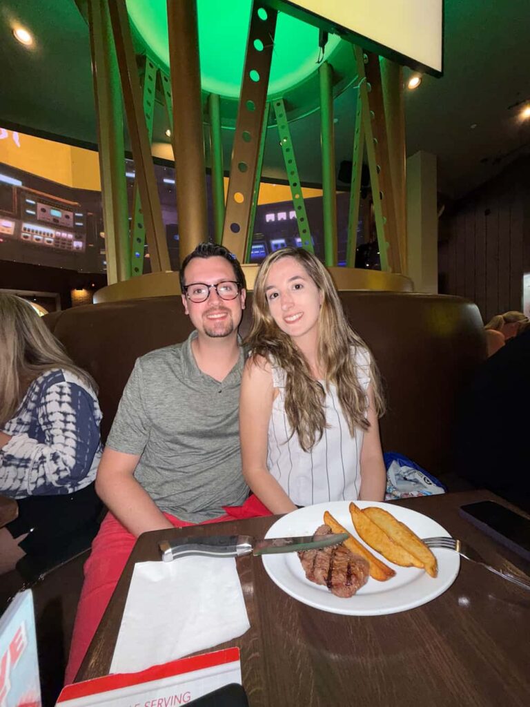 Casal posa sorridente ao jantar no Planet Hollywood, restaurante moderno e temático localizado em Disney Springs, o centro comercial da Disney em Orlando