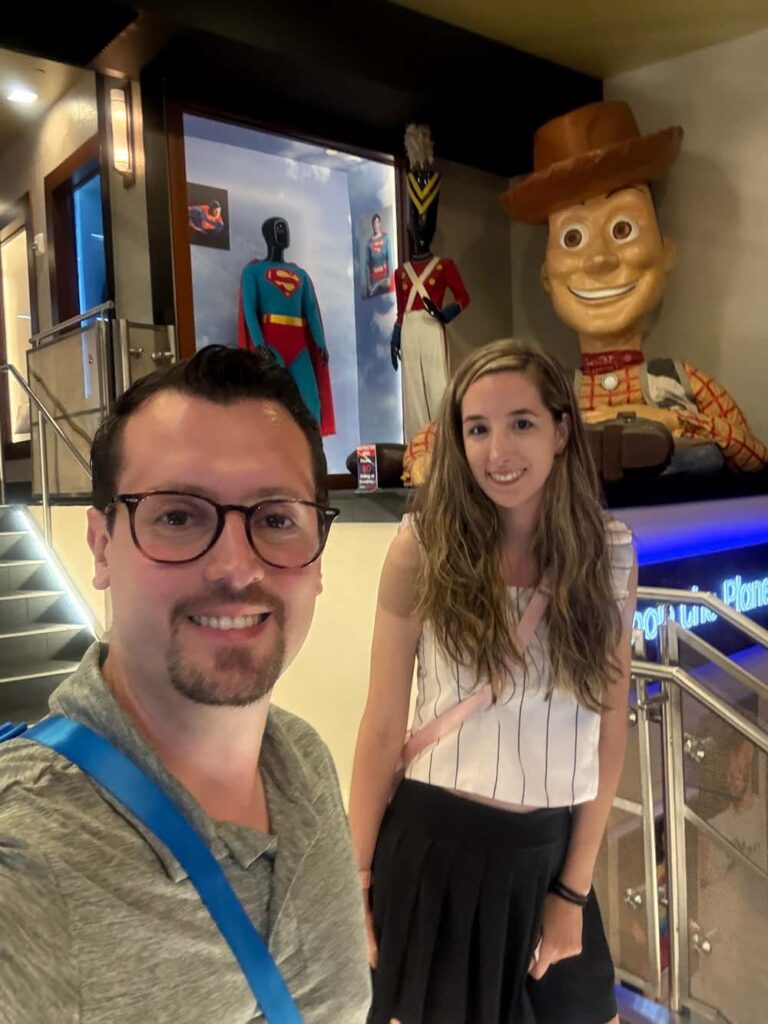 Casal posa sorridente com cenário temático do Planet Hollywood, restaurante moderno e temático localizado em Disney Springs, o centro comercial da Disney em Orlando