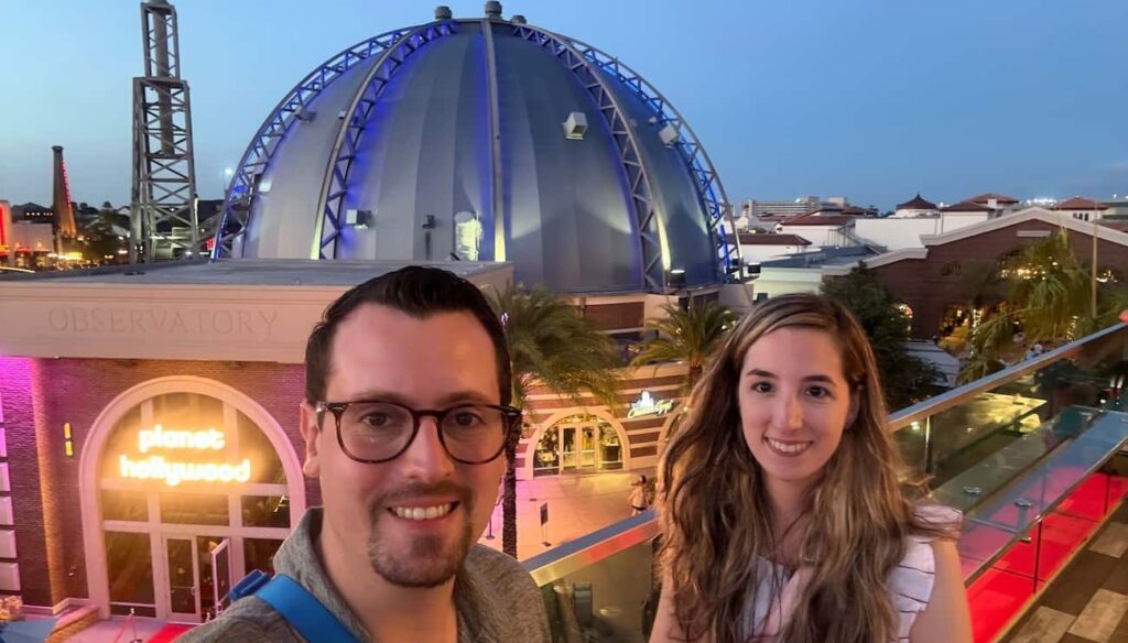 Casal em frente a entrada do Planet Hollywood, restaurante moderno e temático localizado em Disney Springs, o centro comercial da Disney em Orlando