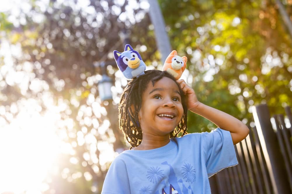 Criança feliz exibe sua tiara personalizada com Buey e Bingo no Animal Kingdom