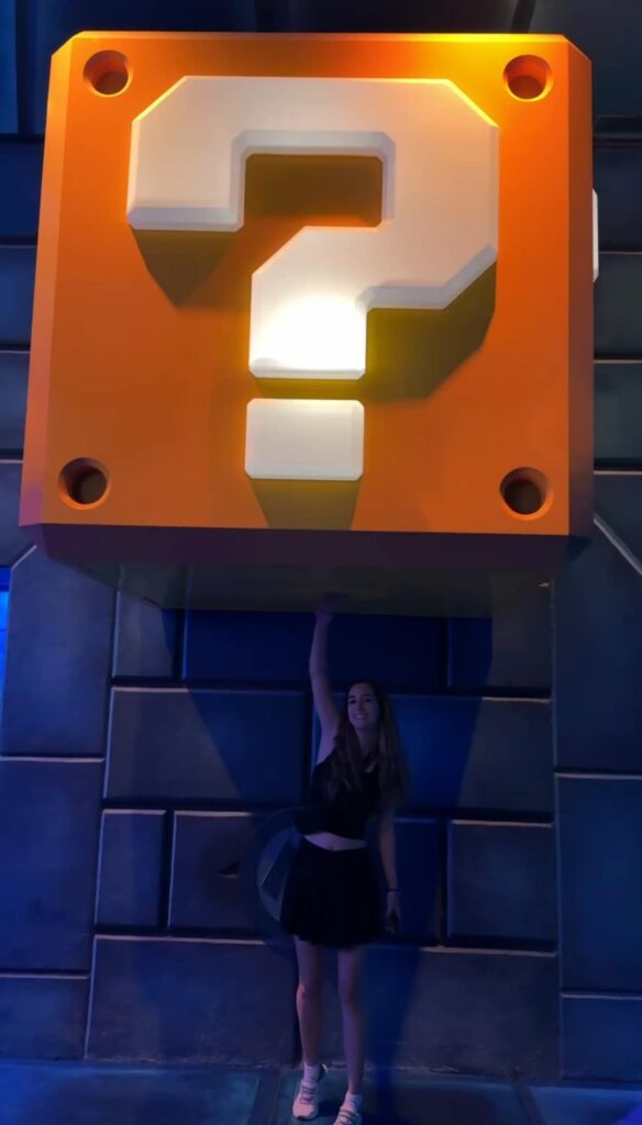 Mulher coleta moedas e bônus em áreas interativas para visitantes que possuem Power Up Band em Nintendo World no Epic Universe da Universal Orlando Resort