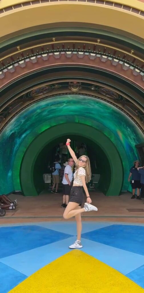 Mulher posa em frente ao portal do Nintendo World no Epic Universe em Orlando com sua Power Up Band