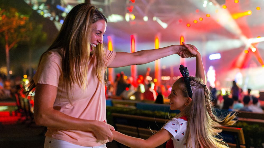 Mãe e filha dançam ao som de apresentação do Eat to the Beat que acontece durante o Food & Wine Festival no Epcot