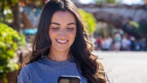 Mulher olha ao celular usando o aplicativo da Universal Orlando Resort durante sua visita aos parques